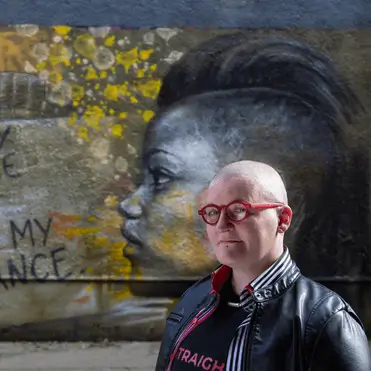 G G in front of a mural